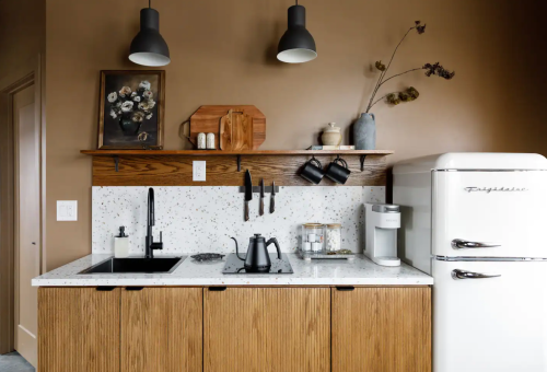 Modern kitchen with wooden cabinets, a speckled countertop, a vintage fridge, and stylish decor.